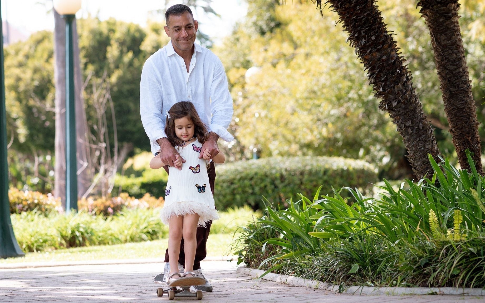man on skateboard with daughter smiling together - WeNatal men’s fertility supplement