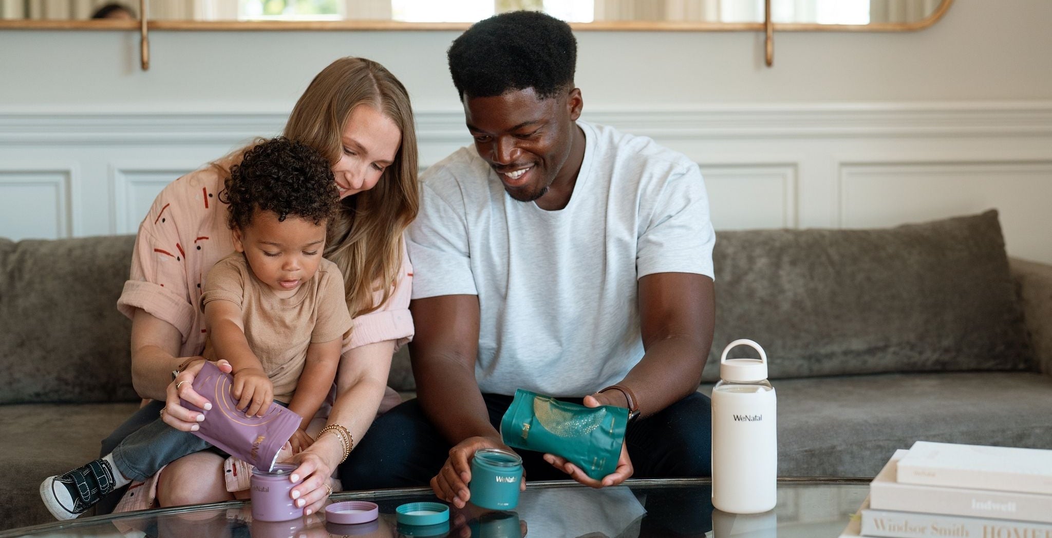 couple sitting on couch with child on their lap filling glass containers from supplement pouch refills - male fertility - WeNatal prenatal