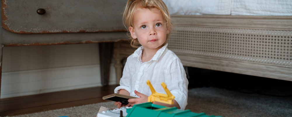 Young child playing with toys on a soft rug in a cozy nursery, showcasing WeNatal's commitment to safe and sustainable baby products