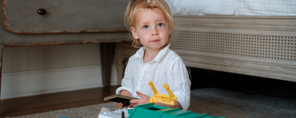 Young child playing with toys on a soft rug in a cozy nursery, showcasing WeNatal's commitment to safe and sustainable baby products.