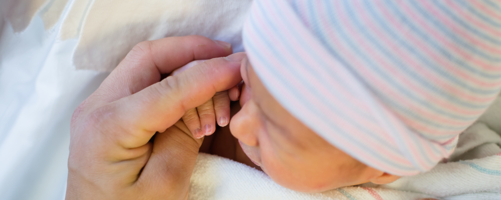 Newborn baby holding an adult's hand, symbolizing hope and the journey of parenthood, as shared in Ronit's story on optimizing fertility at any age - WeNatal