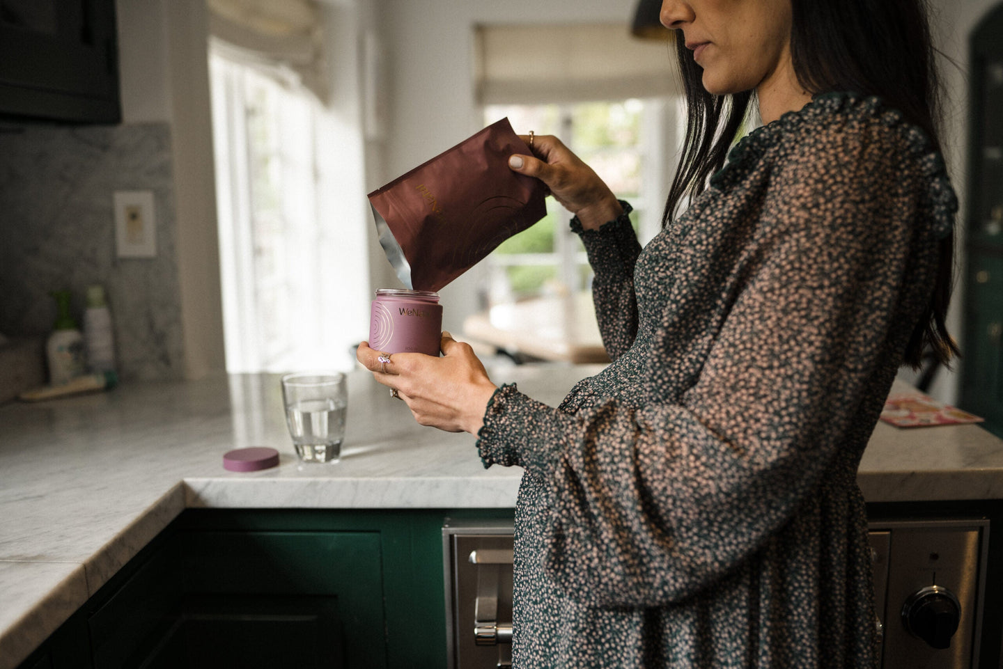 woman refilling bottle of wenatal prenatal - wenatal for her in kitchen - role of vitamin A in pregnancy