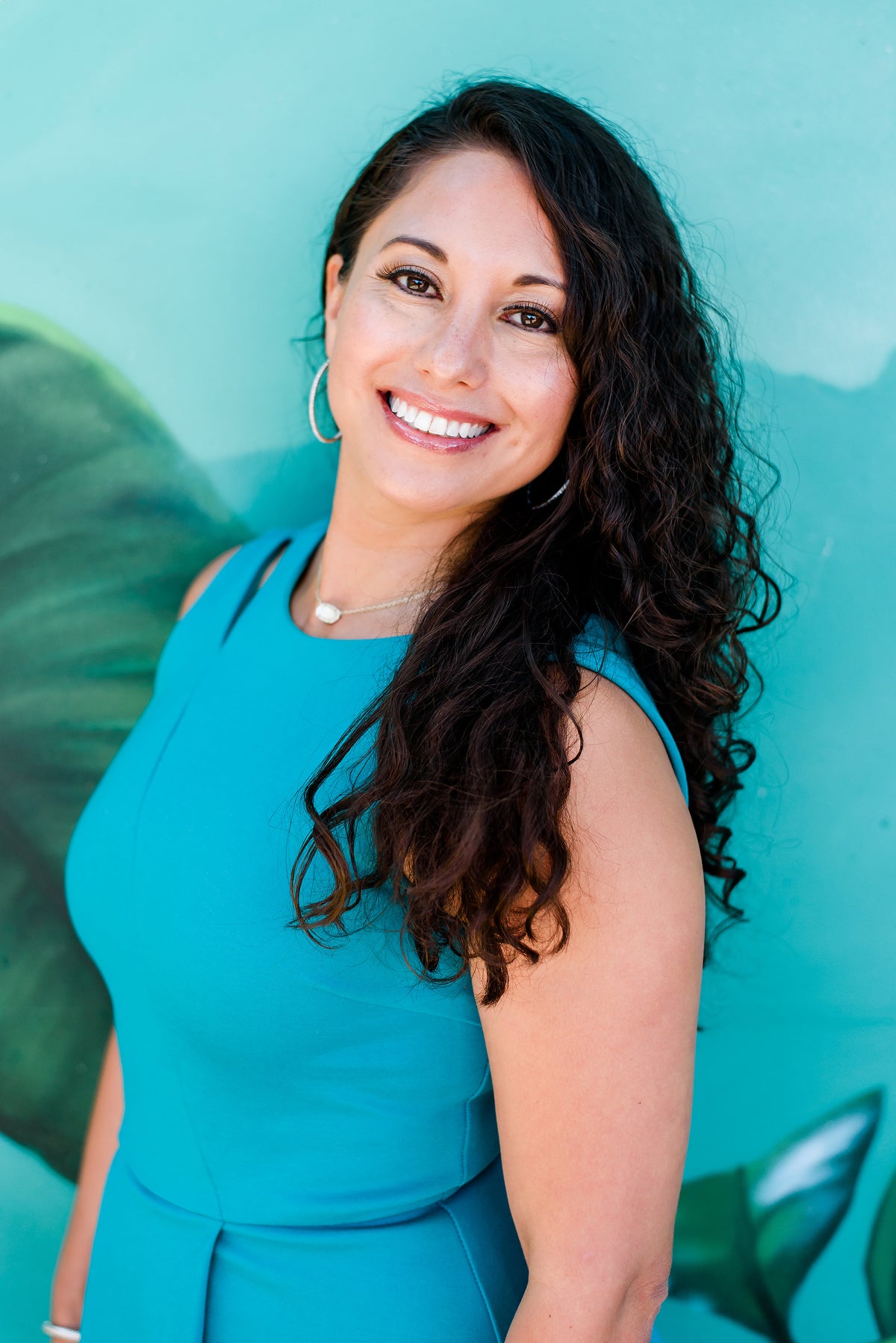 A woman wearing a blue dress smiles at the camera, embodying a positive and healthy lifestyle associated with WeNatal's wellness products.