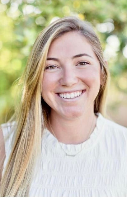 A woman smiling outdoors, reflecting happiness and vitality, aligning with WeNatal's focus on health and well-being