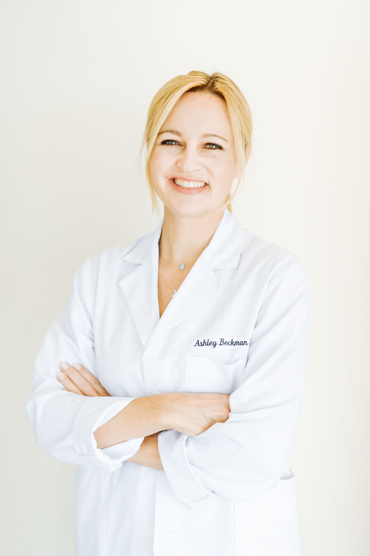 A woman in a white lab coat smiles warmly, reflecting WeNatal's commitment to health and wellness through prenatal vitamin supplements.