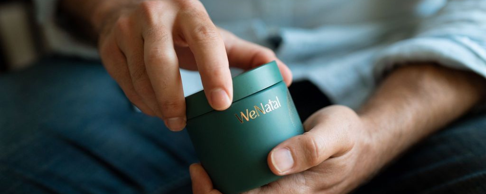 Man sitting on bed holding jar of WeNatal Men's Prenatal vitamins - can men take prenatal vitamins