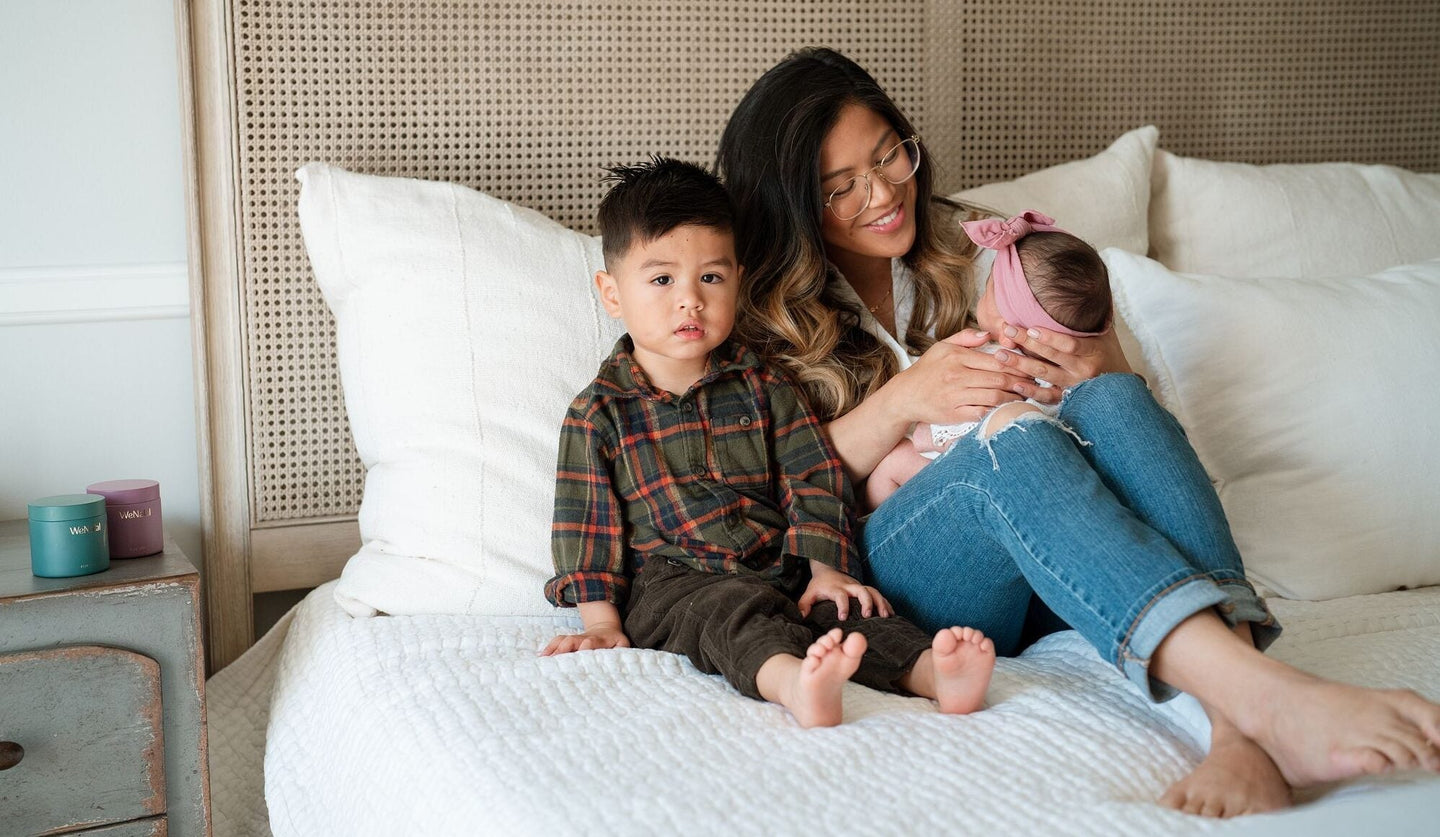 Mother toddler and infant laying on bed together bonding - prenatal vitamins - WeNatal