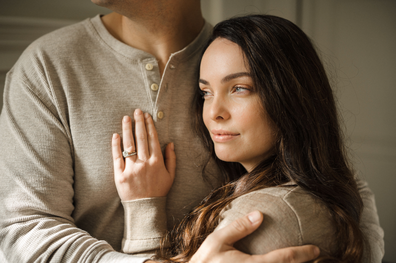 A man and woman embrace, with her hand showcasing a ring, reflecting connection and wellness, themes resonant with WeNatal's prenatal supplements