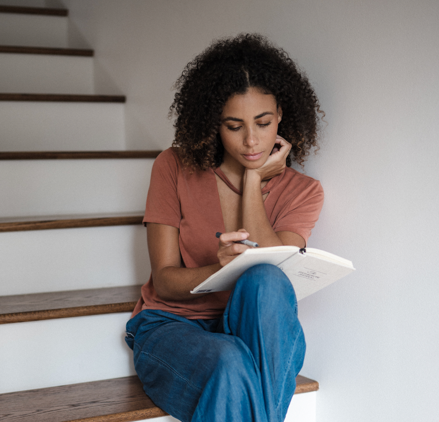 woman sitting on steps journaling - WeNatal manifestation journal - WeNatal prenatal