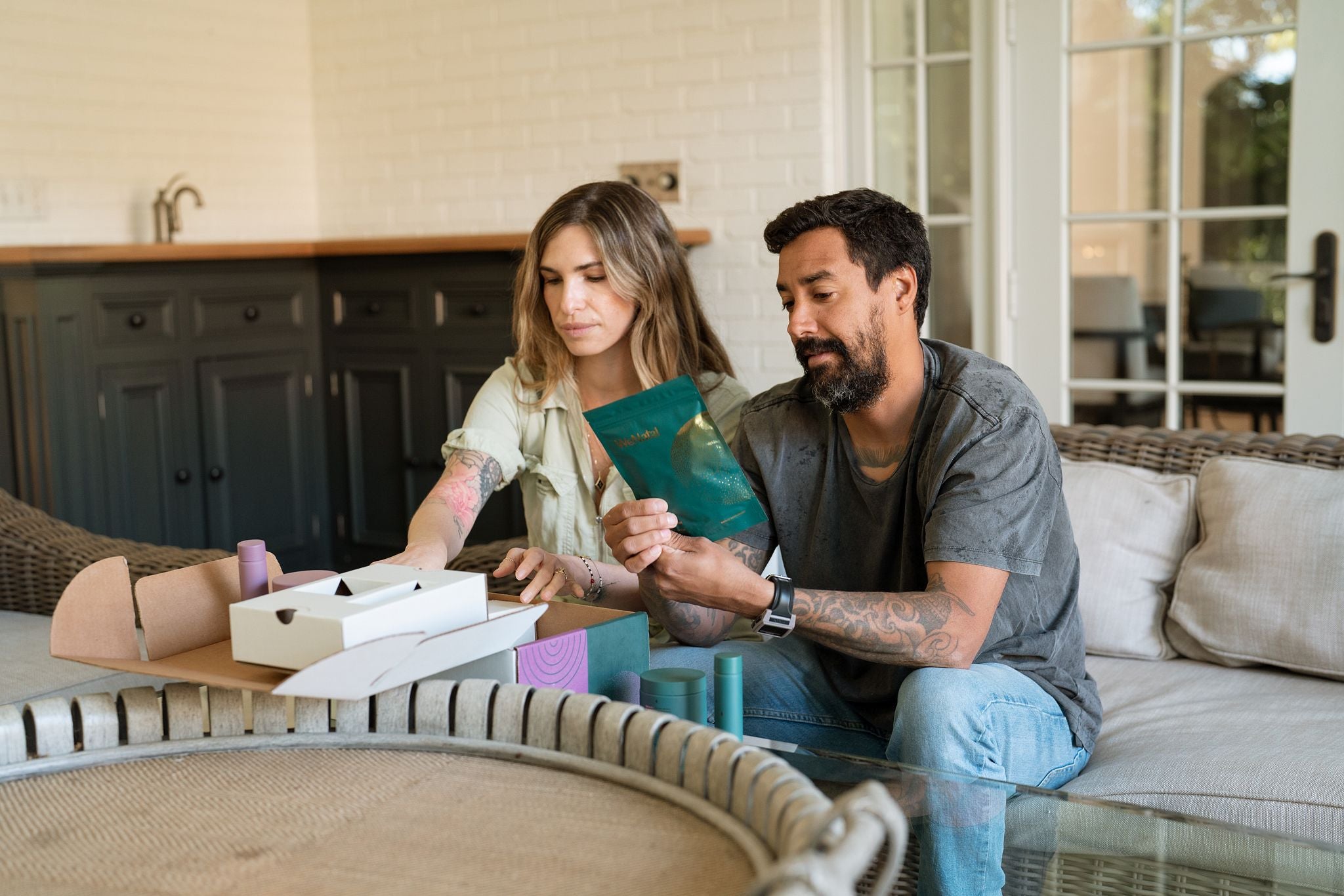 A man and woman on a couch examine a package of prenatal supplements from WeNatal, emphasizing family preparation and male prenatal health