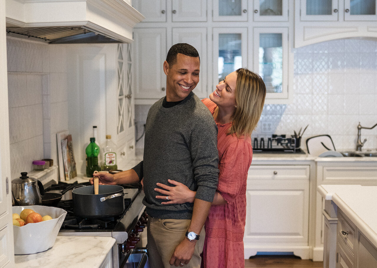 husband and wife in kitchen cooking together - wenatal prenatal - tips to improve your odds of getting pregnant