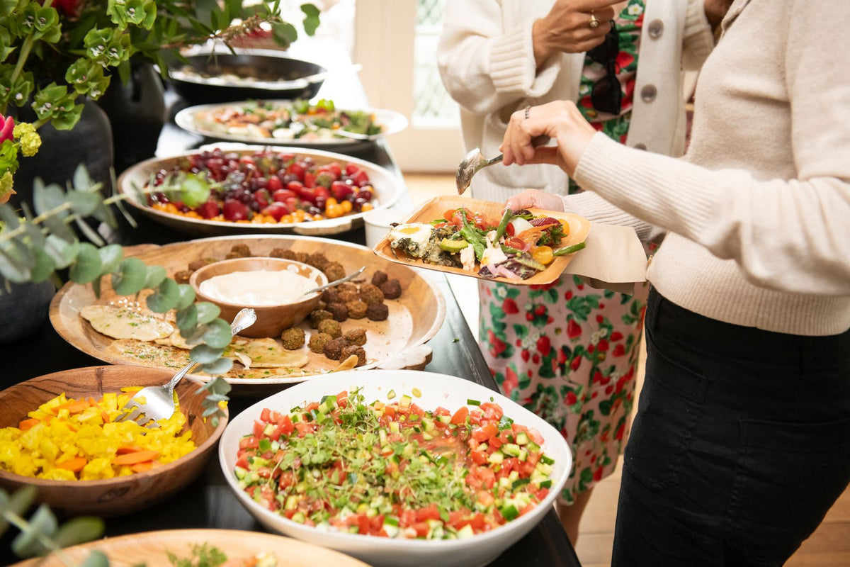 food buffet with lots of colorful salads and dips with women filling their plates - histamine intolerance - WeNatal prenatal vitamins