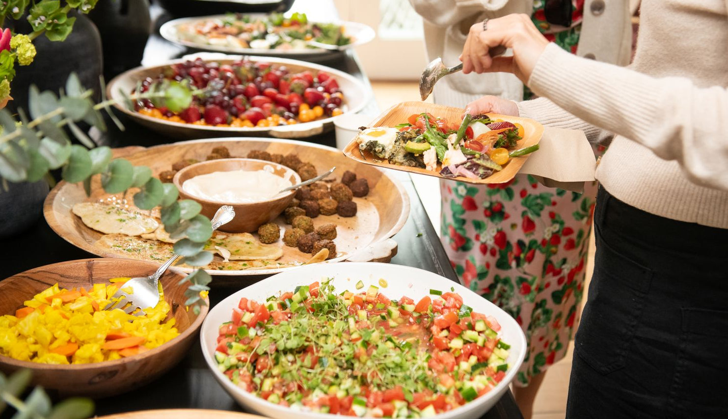 food buffet with lots of colorful salads and dips with women filling their plates - histamine intolerance - WeNatal prenatal vitamins