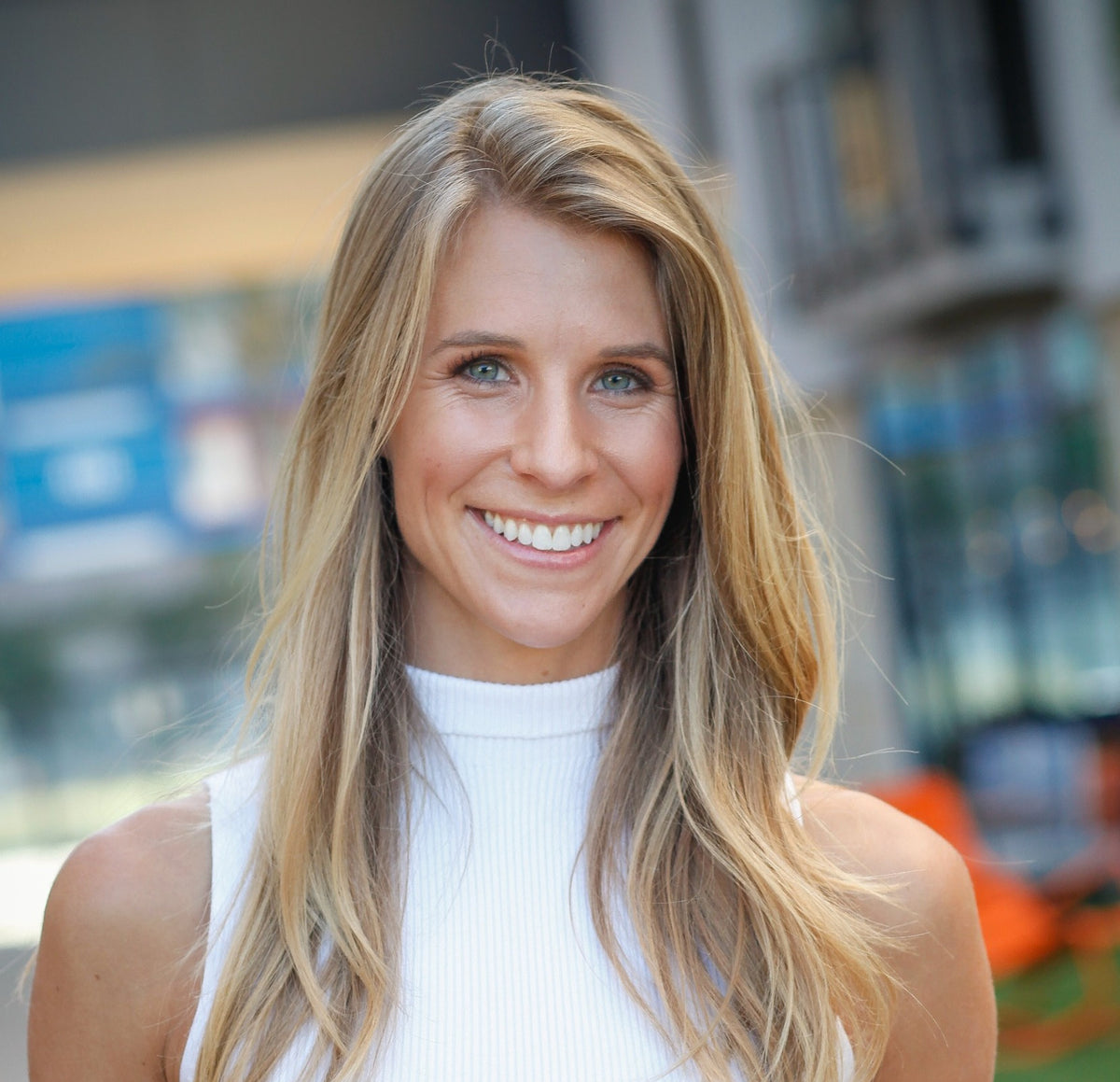 A woman with long, layered brown hair smiling at the camera, symbolizing wellness and positivity, aligned with WeNatal's health-focused products.