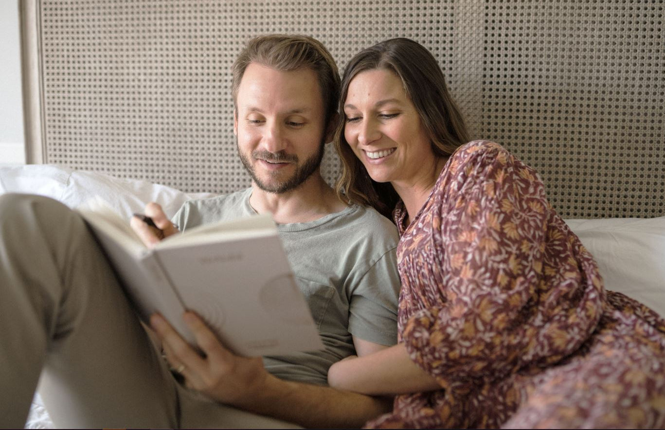 man and woman sitting on bed together journaling - WeNatal Meditation - WeNatal prenatal and fertility supplement