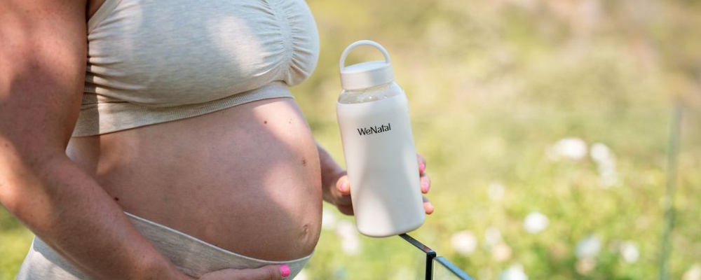 pregnant woman walking with dog outside holding waterbottle - wenatal prenatal - pregnancy blood work