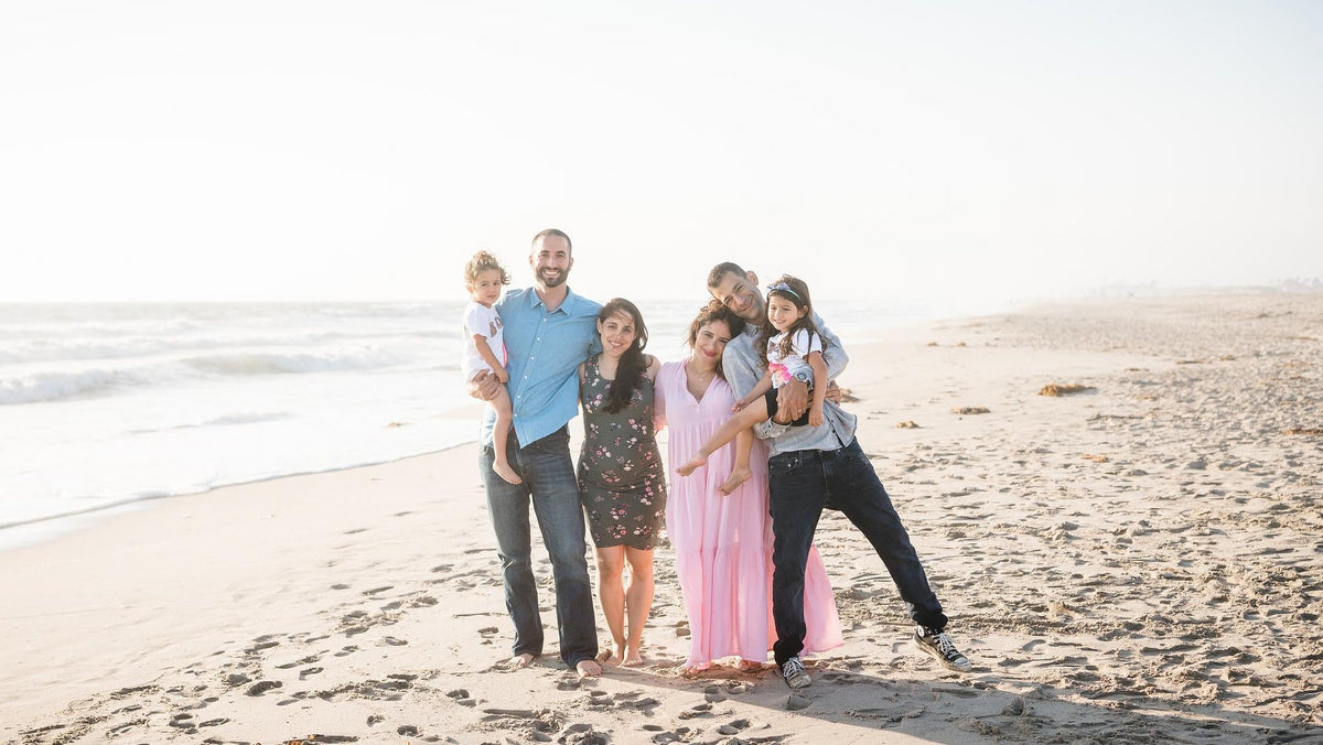 two families with adults and children standing on a beach with the water behind them -pregnancy loss - WeNatal cofounder