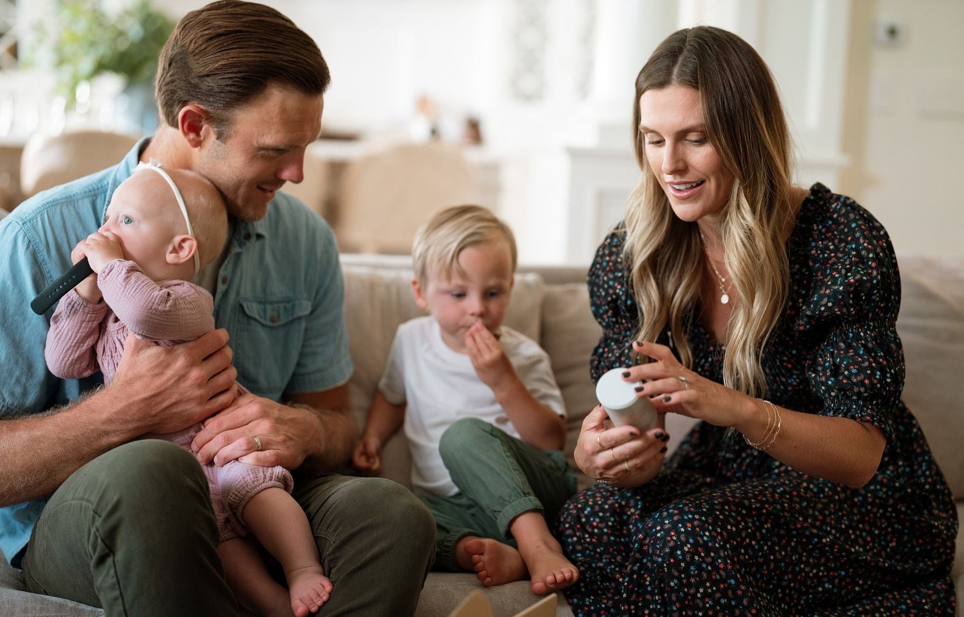 man with baby on lap next to woman with toddler next to her looking at a jar of supplements - WeNatal prenatal