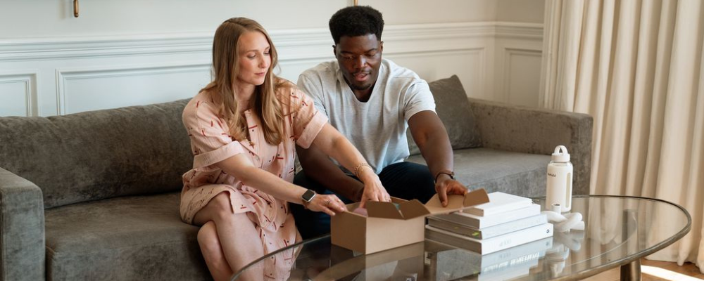 A couple sitting on a couch unboxing WeNatal supplements together, highlighting the importance of teamwork, wellness, and optimizing fertility for both partners.