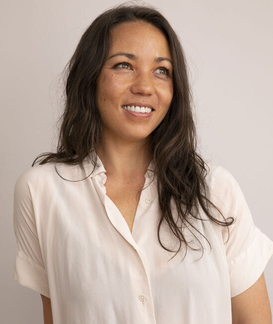 A woman with long hair smiles, wearing a blouse, embodying the spirit of WeNatal's holistic approach to prenatal wellness and lifestyle.