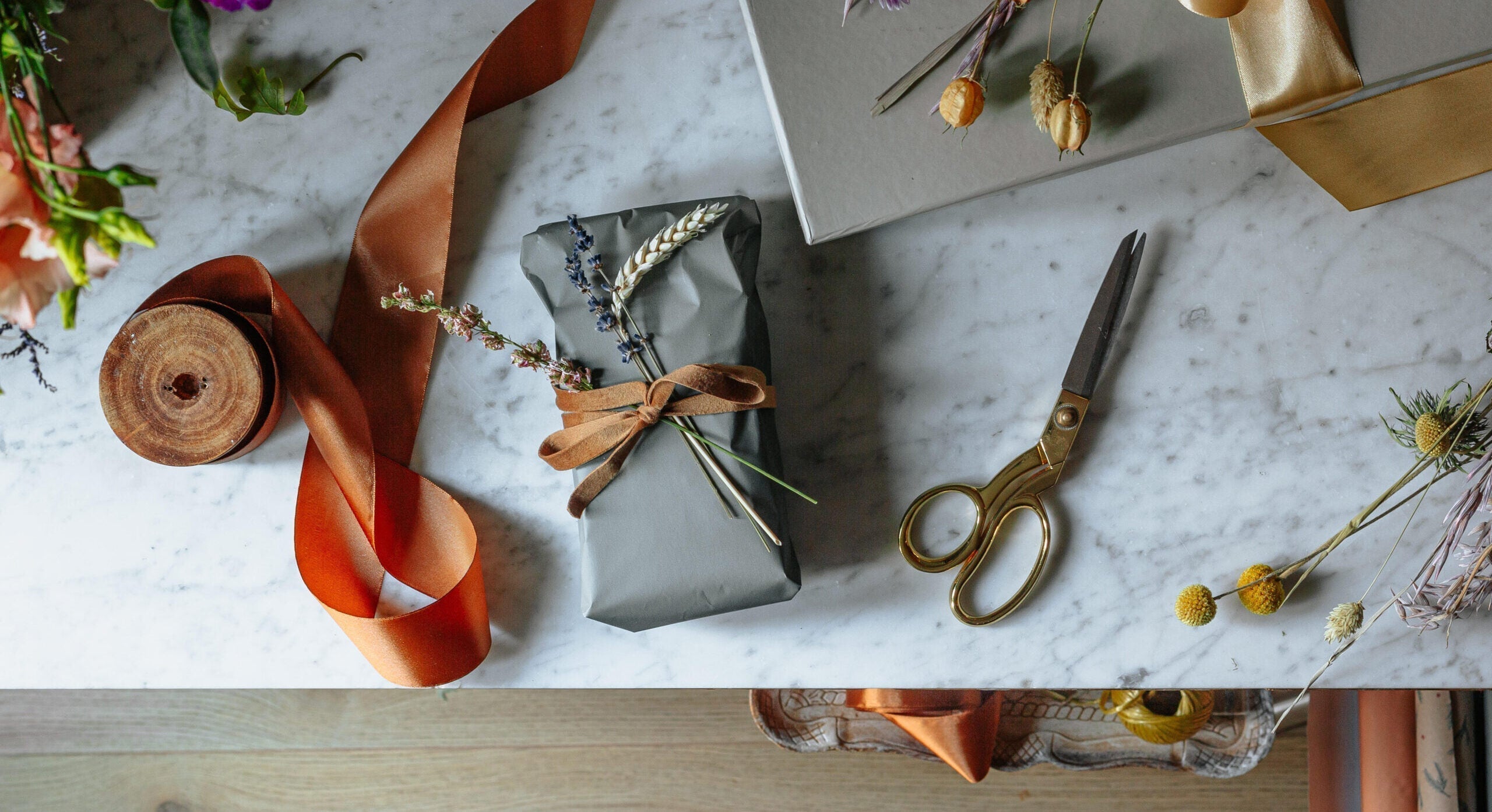 gift on wrapping table with ribbon and scissors - WeNatal Gift Guide - WeNatal Prenatal