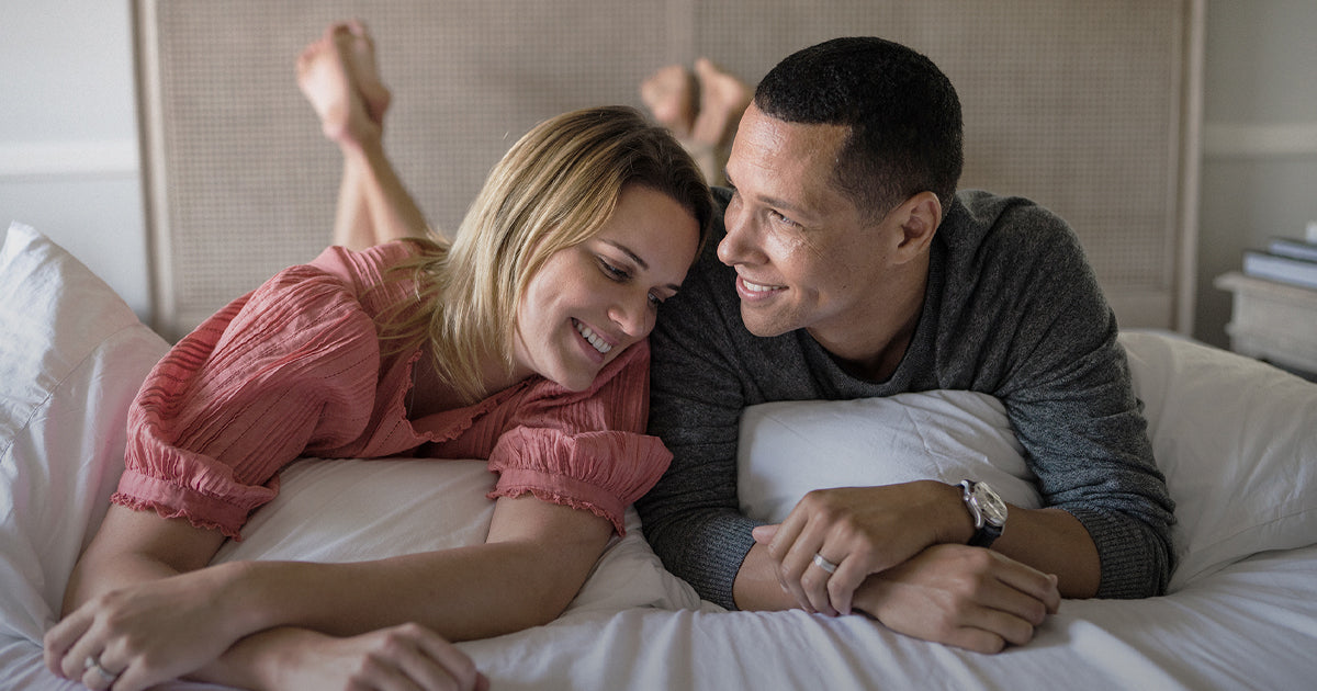 Couple laying on bed chatting - His and Hers prenatal vitamins - WeNatal 