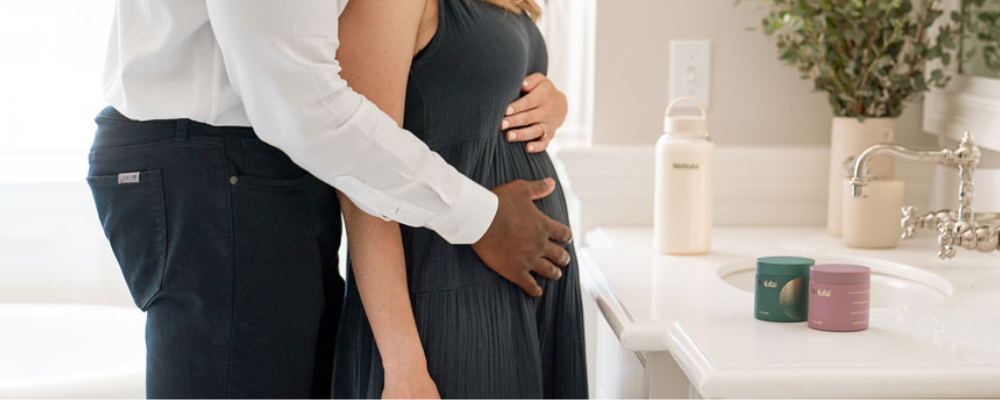 Man embracing a pregnant woman in a bathroom setting.