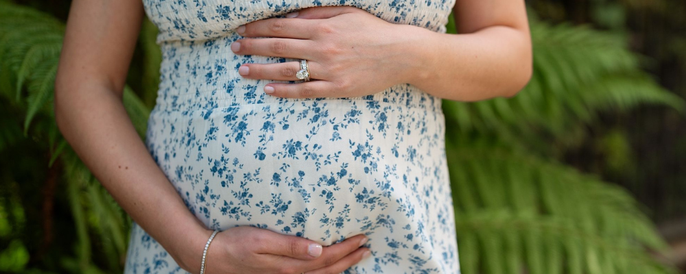 pregnant woman in flora dress holding belly - WeNatal prenatals