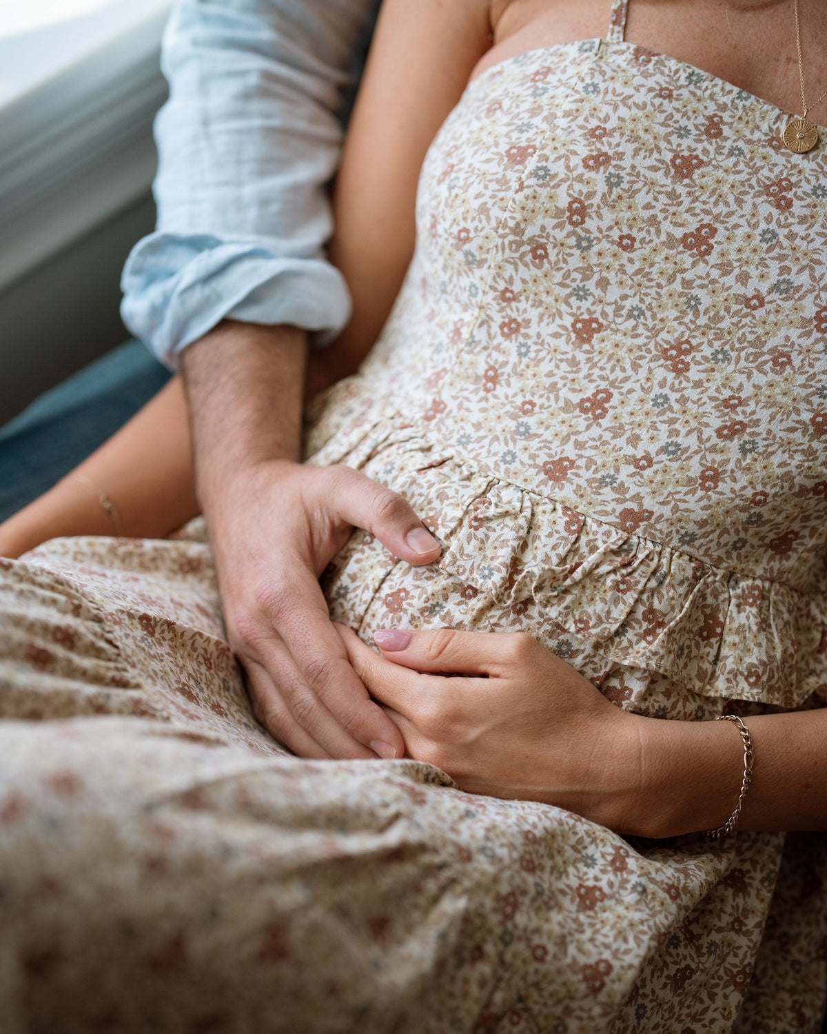 close-up of woman with hands on pregnant stomach with partners hands next to her - WeNatal prenatal - can you get pregnant at 40