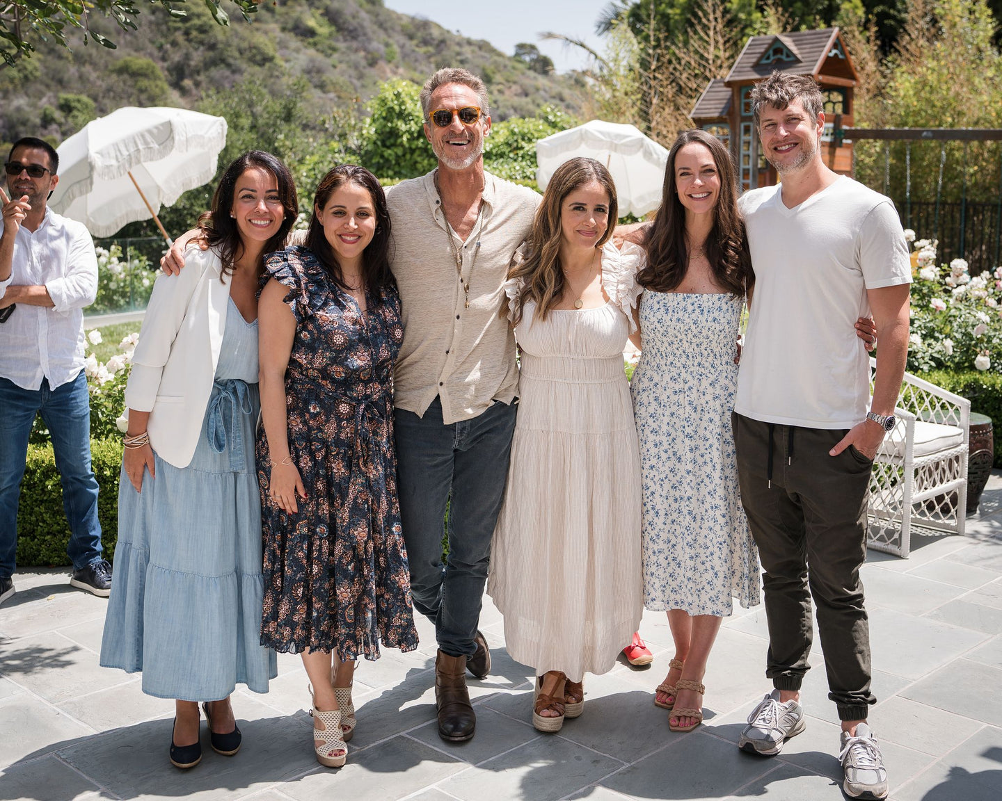 group photo of four girls and 2 guys situated in a backyard with a greenery background. 1 guys was also caught in the background while the group photo was taken.