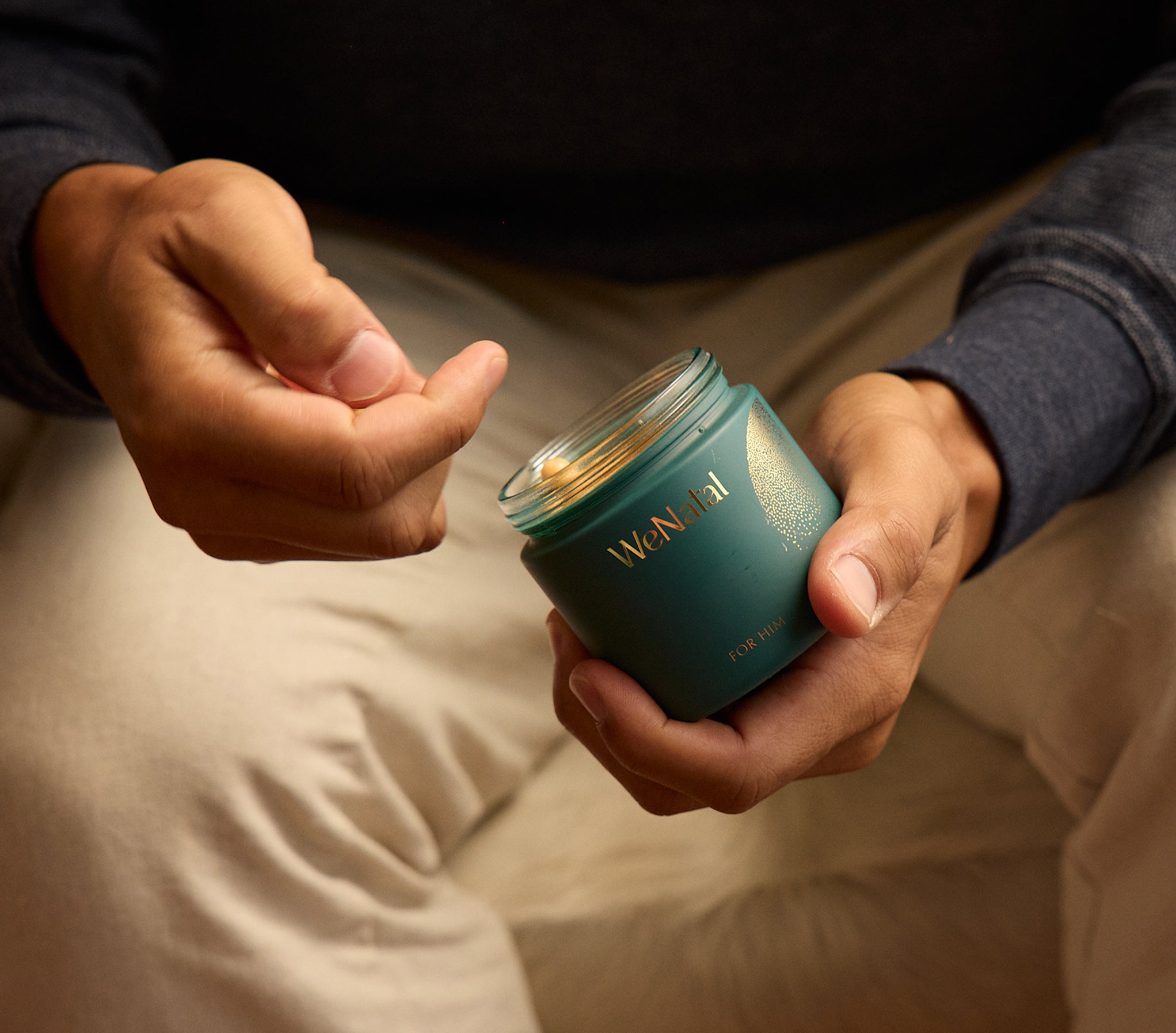 Person holds a WeNatal Together Welcome Kit jar, showcasing golden prenatal supplement capsules for daily nutrient and fertility support, emphasizing prenatal nutrition and essential nutrients
