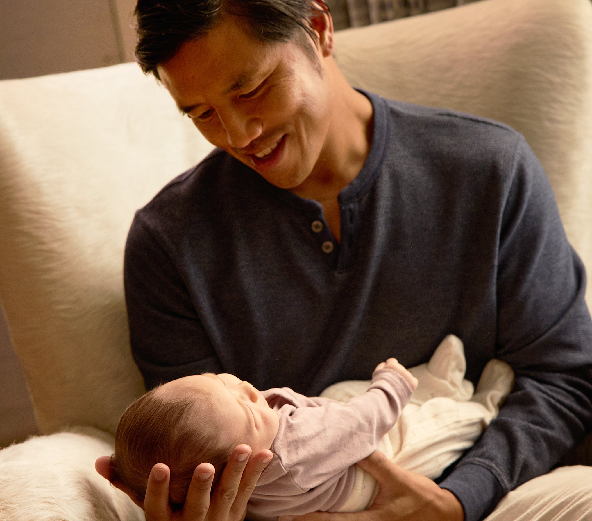 Man cradling newborn in warm bonding moment, showcasing WeNatal For Him Welcome Kit, a prenatal supplement offering daily nutrient and fertility support in capsule form