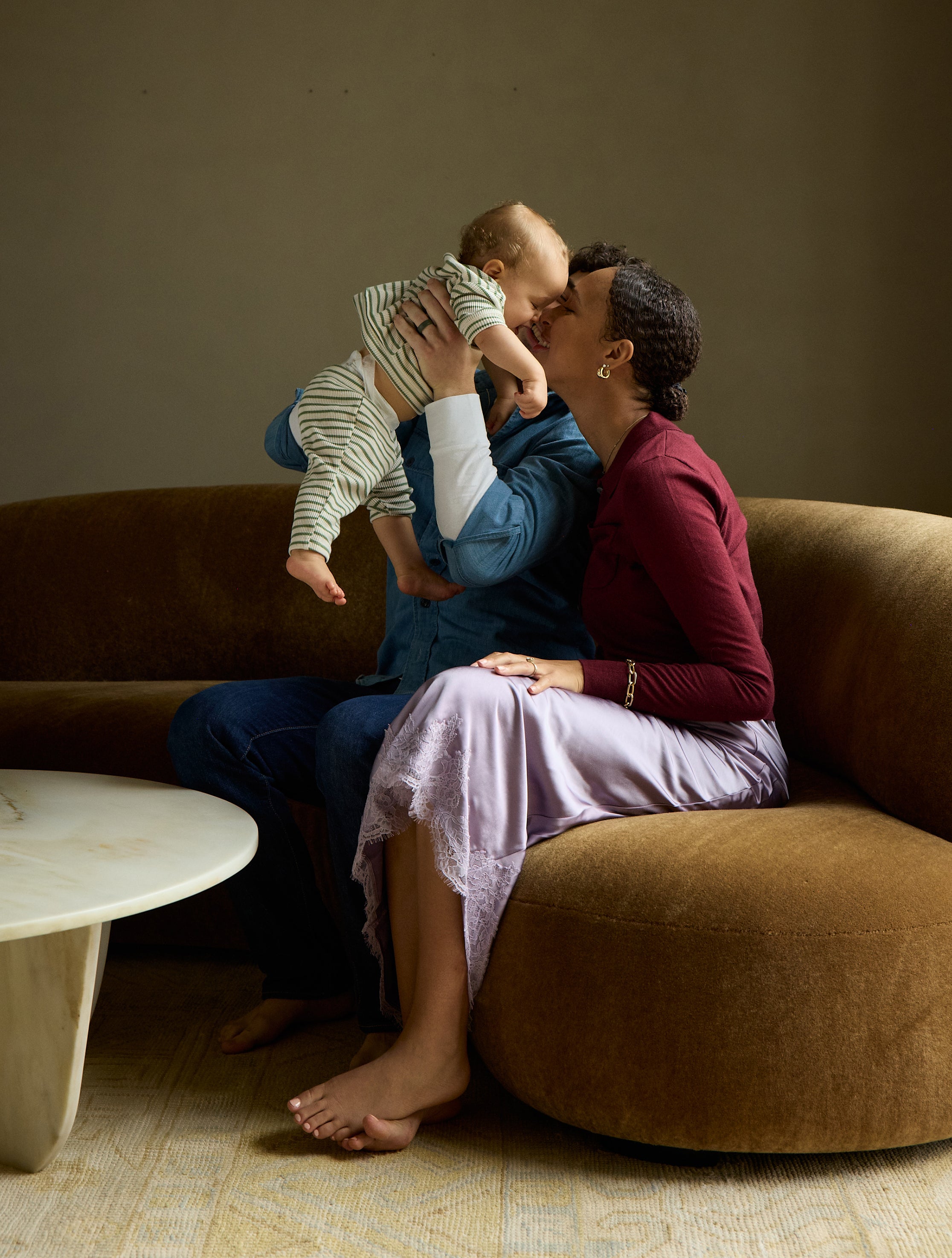 Couple enjoys a cozy moment with their baby, highlighting WeNatal Affirmation Cards on the coffee table, symbolizing prenatal support and wellness in a nurturing setting