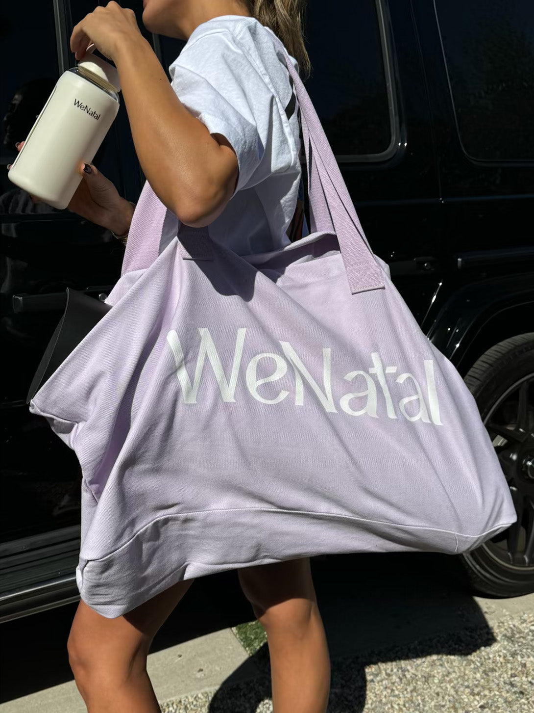 Woman carrying Free Everything Tote and a water bottle, highlighting the tote's spacious design and versatility for various activities.