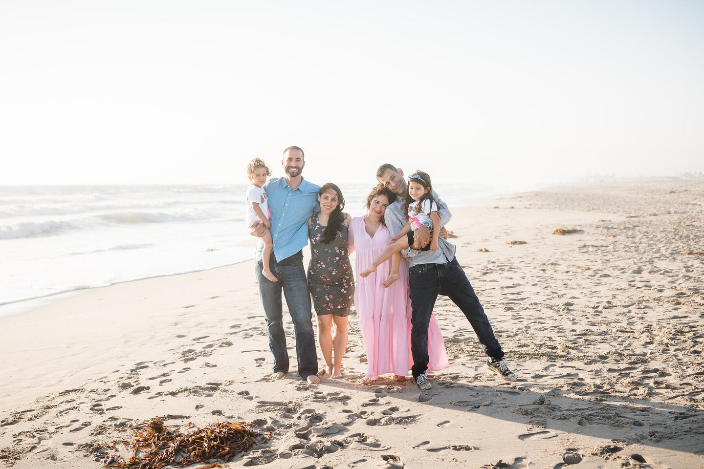 two families with adults and children standing on a beach with the water behind them -pregnancy after miscarriage