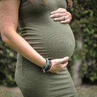 A photo of a woman's pregnant belly while she is caressing it