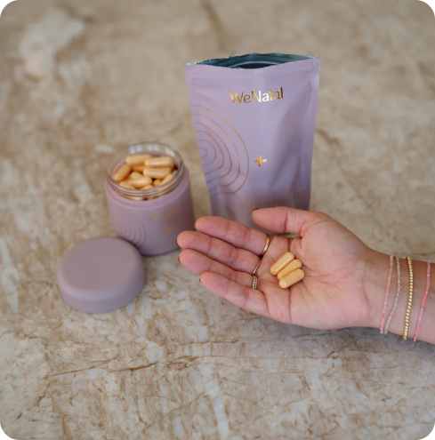 WeNatal Egg Quality + Welcome Kit on a counter with 3 pills in a womens hand 