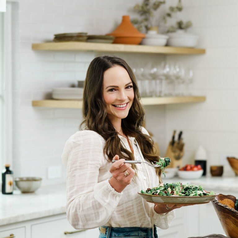half body photo of Kelly Leveque, CCN holding a fork and a plate with salad on it