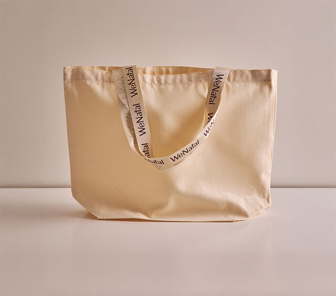 The WeNatal Tote, a natural canvas bag with WeNatal on the handles, embodies the brand's focus on daily and prenatal nutrient support.